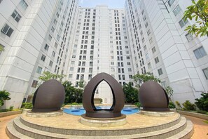 Un edificio moderno con un cortile centrale che include una scultura particolare e una piscina.