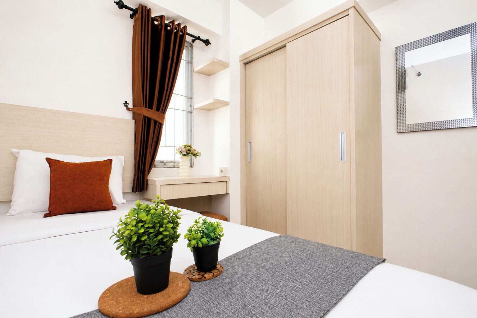 A modern bedroom with a bed, a bedside table, a mirror, and a wardrobe.
