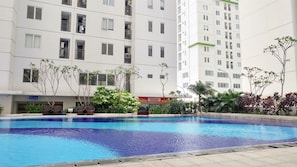 Una piscina circondata da un edificio residenziale con balconi e un cartello di un negozio visibile.