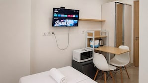 A hotel room with a bed, a desk, a microwave, a TV displaying 'Avengers', and a door. - Good Minimalist Studio Room At Apartment Bandaraya - Tallasa City Makassar (Makassar (Ujung Pandang))