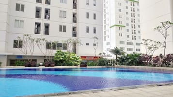 Una piscina circondata da un edificio residenziale con balconi e un cartello di un negozio visibile.