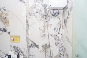 Un bagno con doccia, WC e lavandino. C'è un cartello appeso al muro e una bottiglia di sapone per le mani sul ripiano.