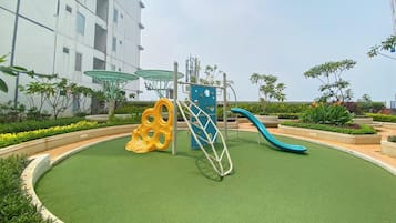 Un'area giochi con uno scivolo, una struttura di arrampicata e uno scivolo a spirale giallo.