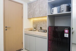 Cocina compacta con puerta de madera, encimera de mármol, horno integrado y refrigerador con etiqueta halal.