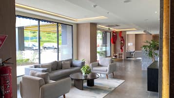 A modern hotel lobby with a sofa, chairs, a coffee table, and a reception desk.