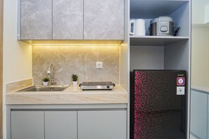 Una cocina con encimera de mármol, un fregadero, una pequeña planta en maceta, un tostador y un refrigerador con un estampado geométrico rojo.