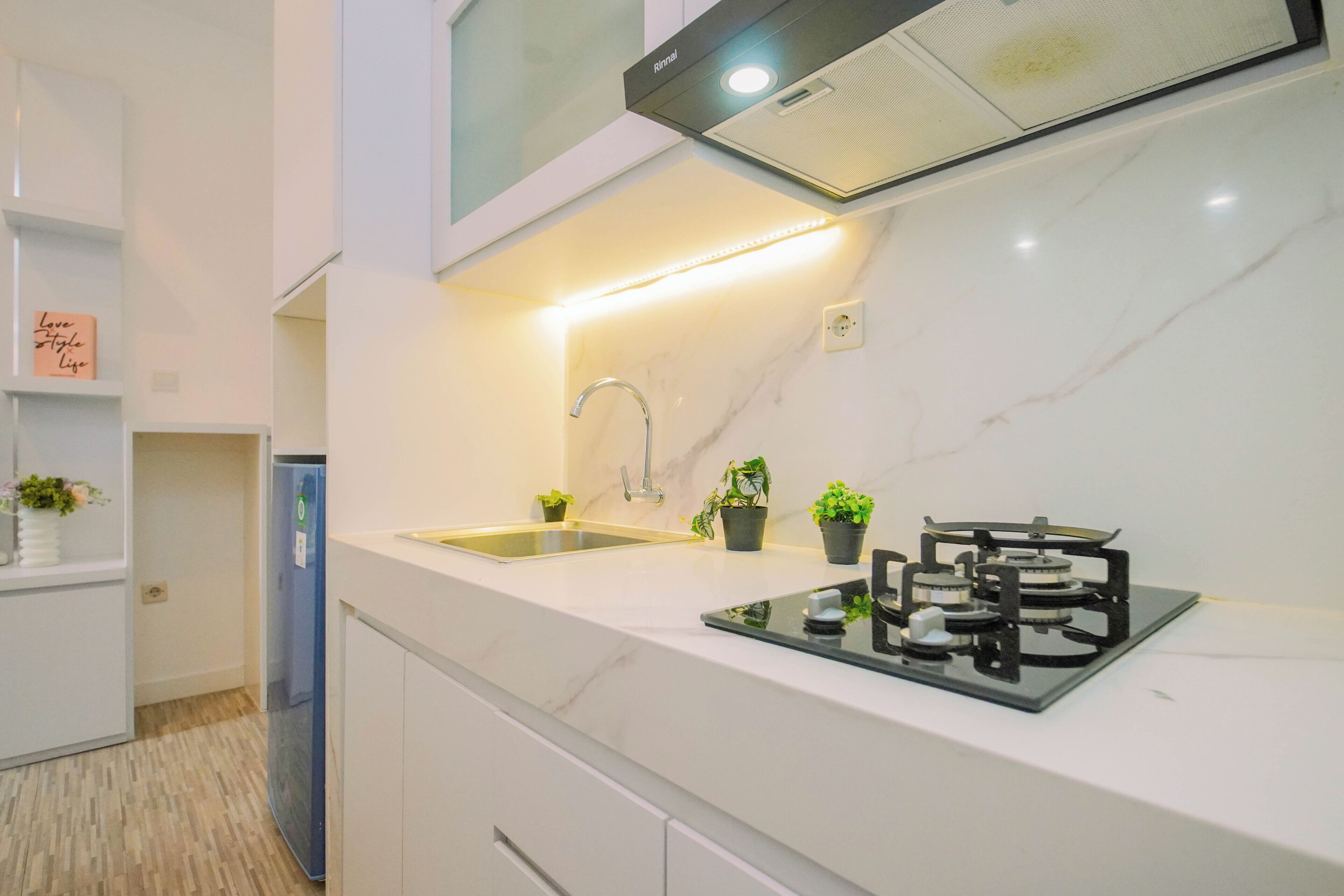 Una cocina moderna con estufa a gas integrada, un lavaplatos de acero inoxidable y un refrigerador compacto.