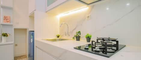 Una cocina moderna con estufa a gas integrada, un lavaplatos de acero inoxidable y un refrigerador compacto.