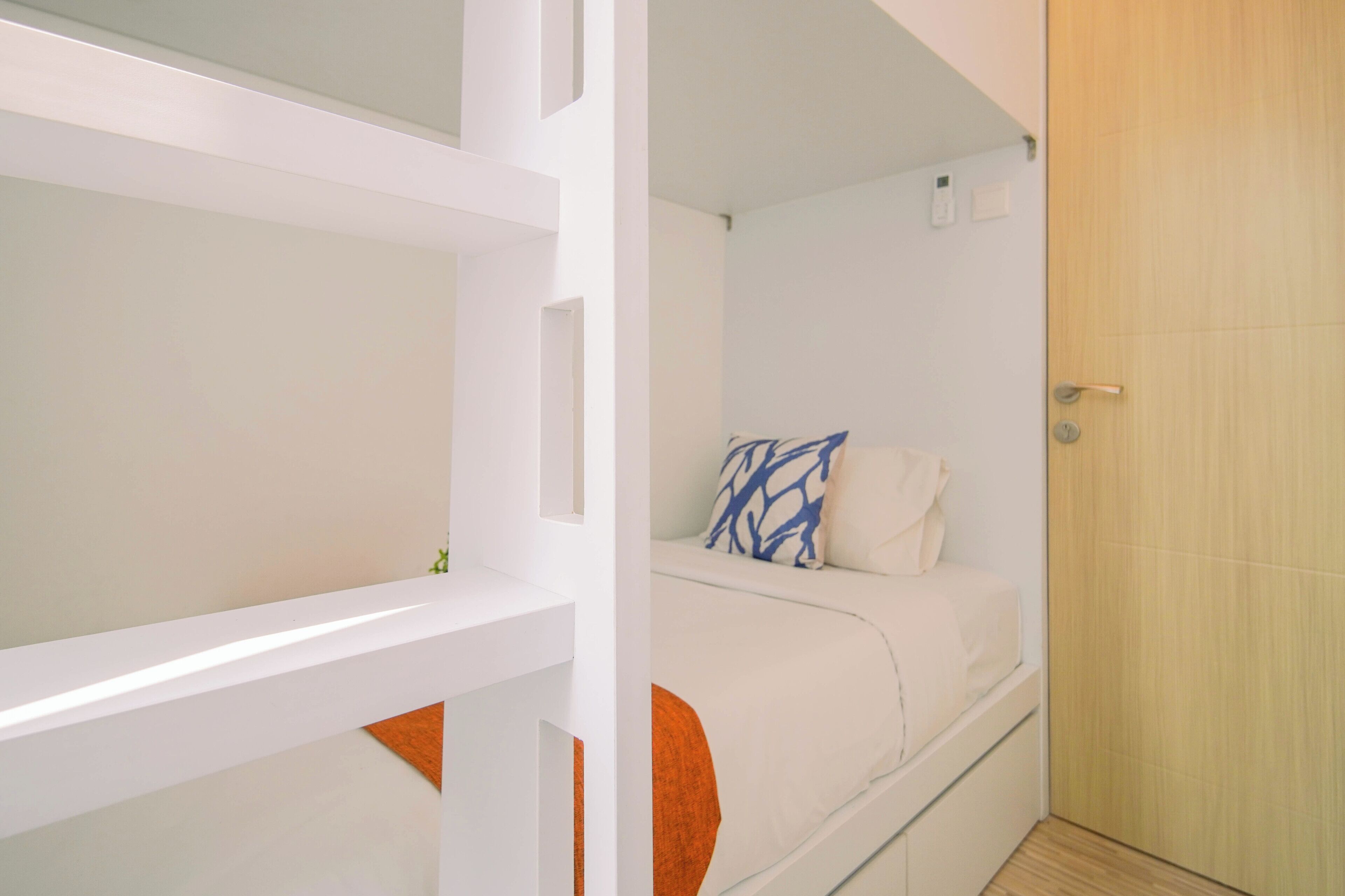 Ein modernes Hotelzimmer mit einem Bett, einer Tür und einem kleinen Fenster.