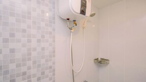 A bathroom with a shower, a towel rack, and a wall-mounted electric water heater. - Warm Minimalist 2Br At Apartment Tokyo Riverside Pik 2 (Jakarta)
