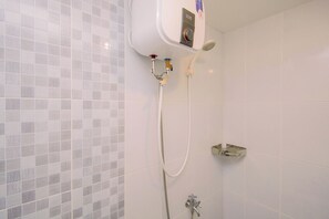 Ein Badezimmer mit Dusche, Handtuchhalter und einem an der Wand montierten elektrischen Warmwasserbereiter.