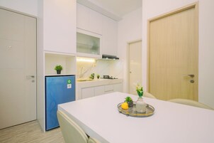 A compact kitchen with white cabinets, a blue refrigerator, and a dining area with a tray of food.