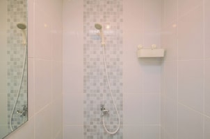 A bathroom with a shower, a mirror, and a soap dispenser.