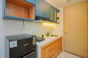 A compact kitchen with a black refrigerator, a sink, wooden cabinets, and a blue upper cabinet.