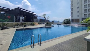 A swimming pool with metal railings, surrounded by a tiled deck and potted plants. - Urban Cozy Studio At Apartment Skyland City Jatinangor (Sumedang)