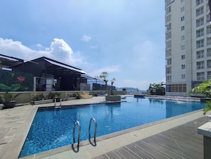 A swimming pool with metal railings, surrounded by a tiled deck and potted plants. - Urban Cozy Studio At Apartment Skyland City Jatinangor (Sumedang)
