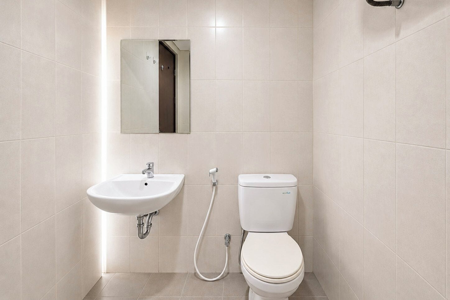 A bathroom with a white sink, toilet, and a mirror above the sink.