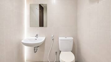 A bathroom with a white sink, toilet, and a mirror above the sink.