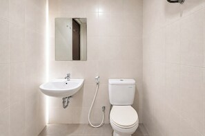 A bathroom with a white sink, toilet, and a mirror above the sink. - Urban Cozy Studio At Apartment Skyland City Jatinangor (Sumedang)