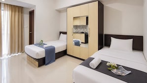 A hotel room with two beds, a wardrobe, a bathroom, and a small kitchenette. - Urban Cozy Studio At Apartment Skyland City Jatinangor (Sumedang)