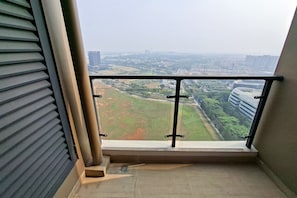 A balcony with a metal railing, a view of a cityscape, and a building with a 'Travelers' sign. - Beautifully Designed 2Br At Apartment Sky House Bsd (Pagedangan)