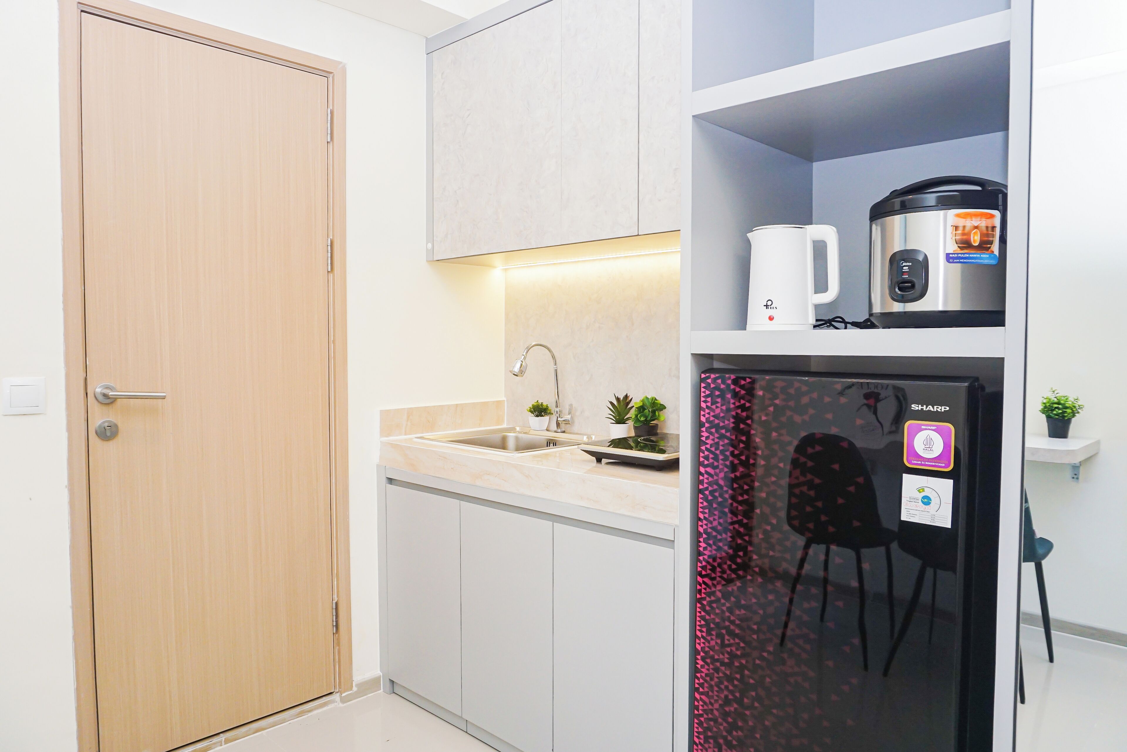 A compact kitchen with a sink, a coffee maker, a rice cooker, and a refrigerator with a water dispenser.