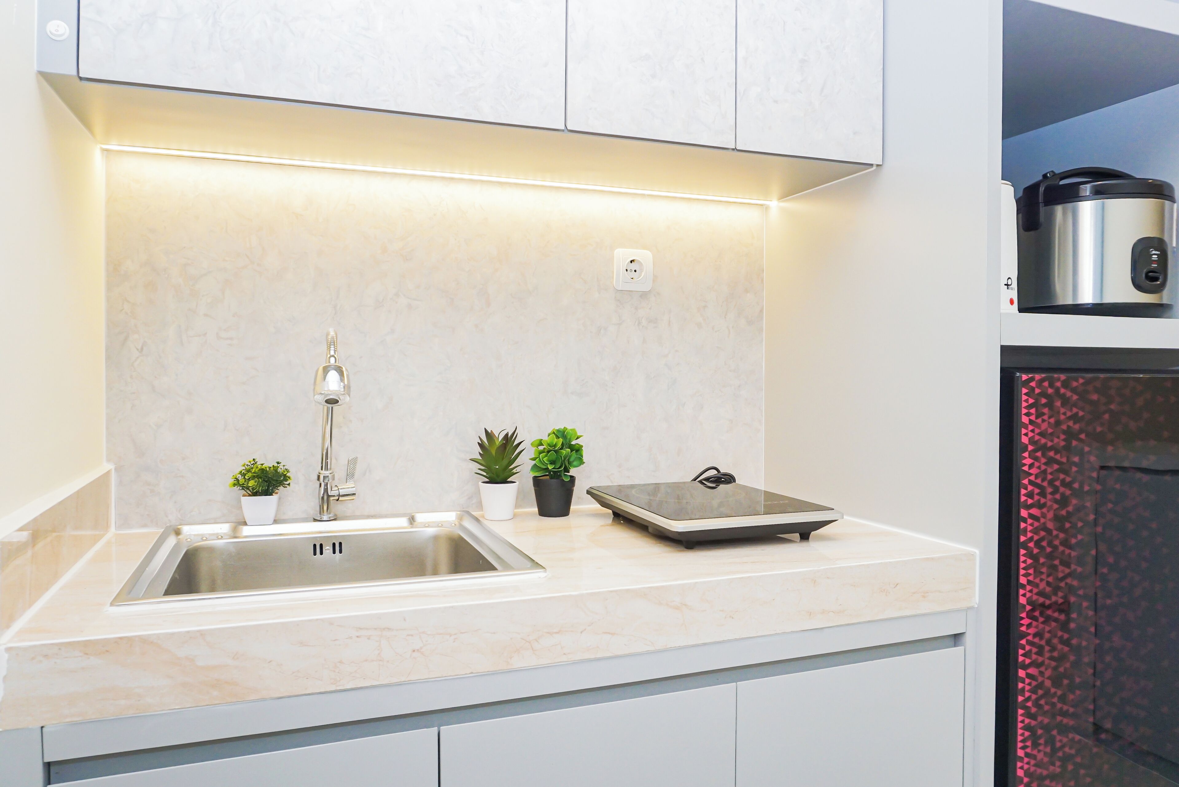 Una cocina moderna con un lavamanos de acero inoxidable, horno empotrado y una encimera con plantas en macetas.