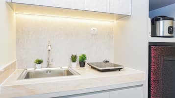 Una cocina moderna con un lavamanos de acero inoxidable, horno empotrado y una encimera con plantas en macetas.