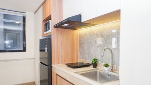 Una cucina moderna con forno a microonde integrato, elettrodomestici in acciaio inossidabile, un lavello con rubinetto e una piccola pianta in vaso.
