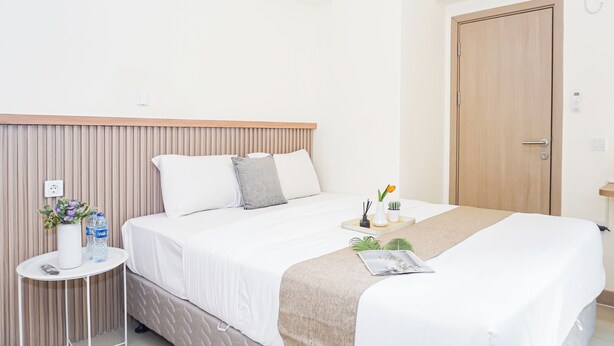 Una camera d'albergo con un letto, un comodino e una porta.