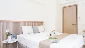 Una habitación de hotel con una cama, mesita de noche y una puerta.