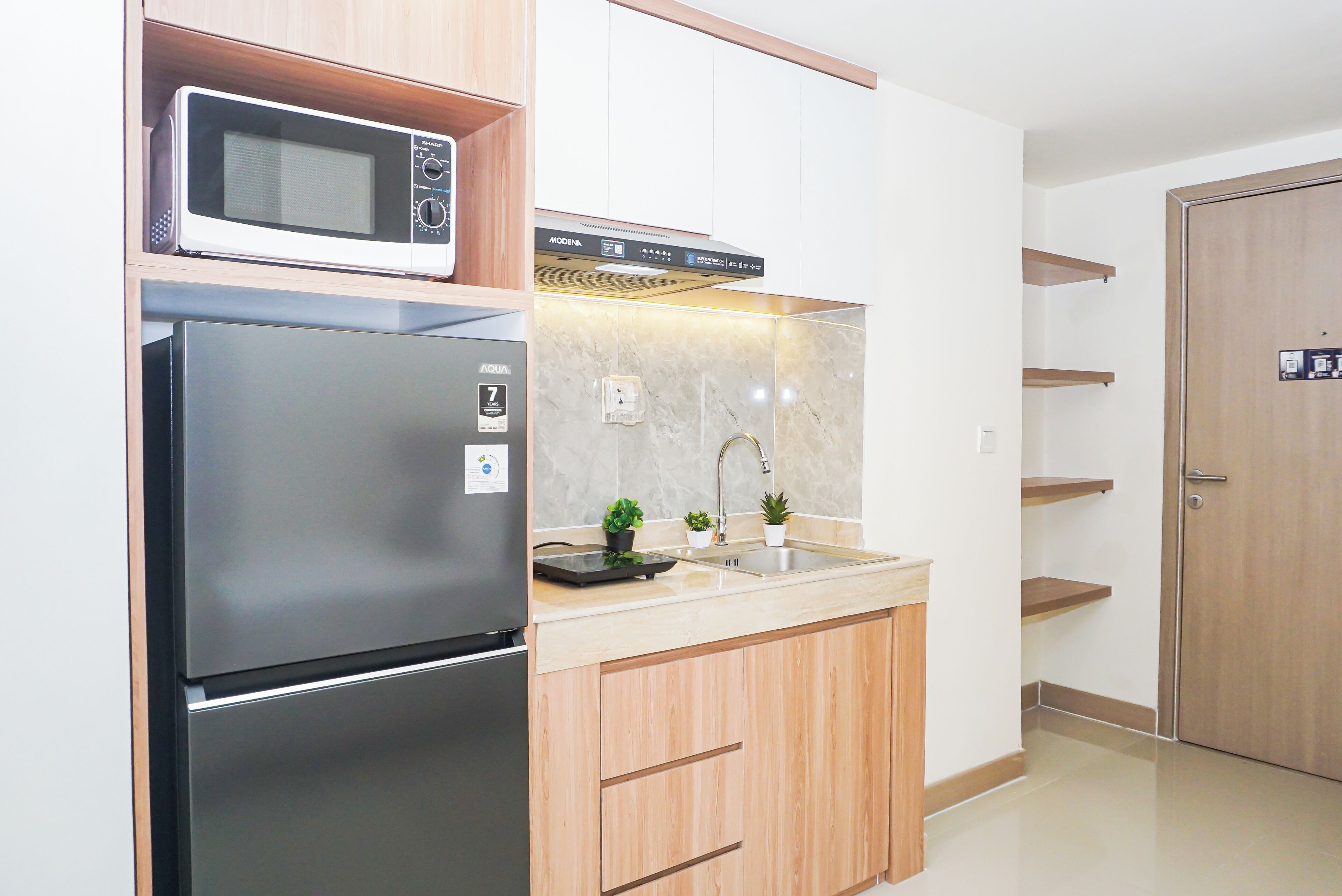 A compact kitchen with a refrigerator, microwave, and a sink with a modern faucet.