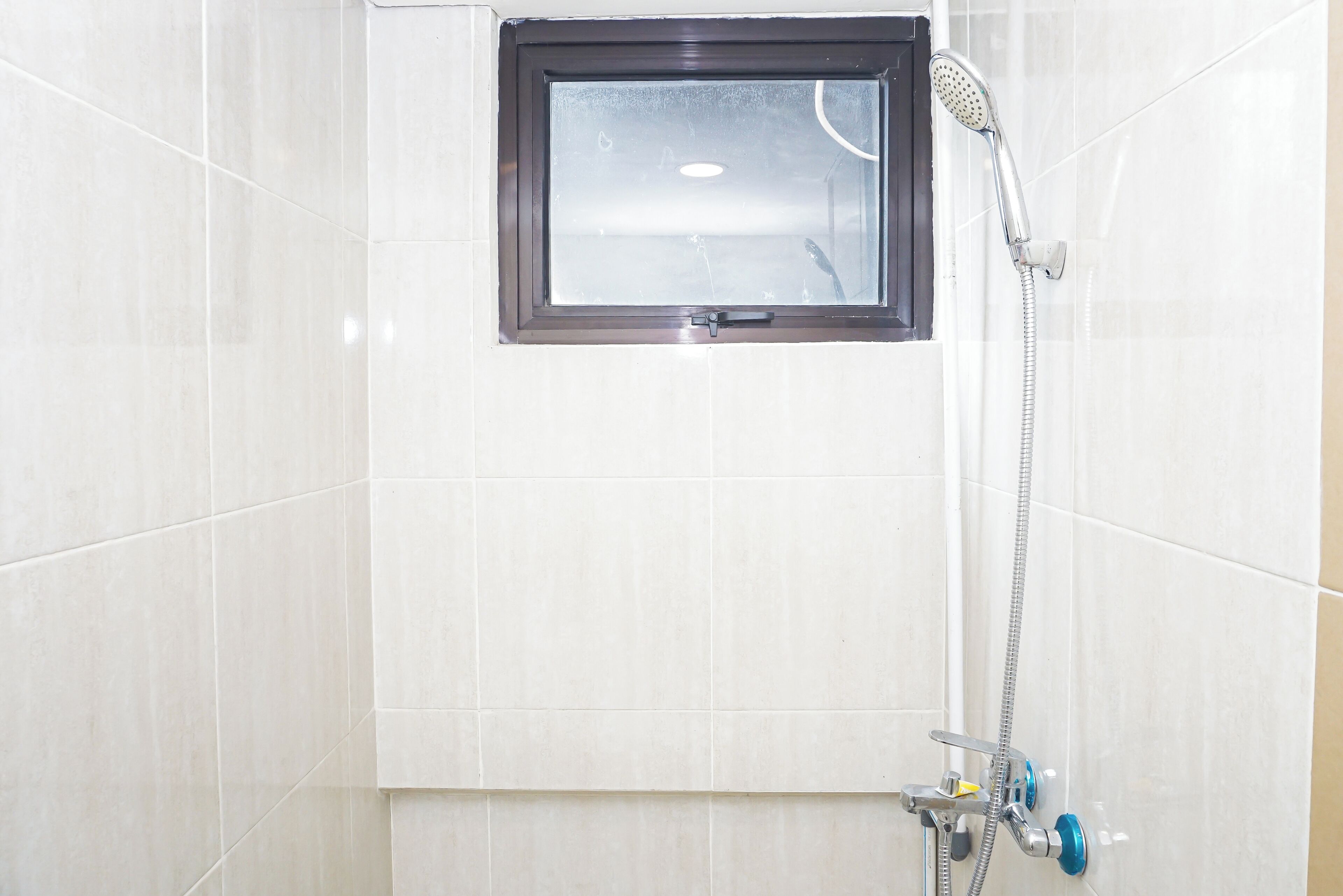 Ducha con ventana, cabezal de ducha de mano y grifería empotrada.