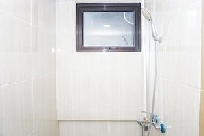 Eine Dusche mit Fenster, einer Handbrause und einer wandmontierten Armatur.