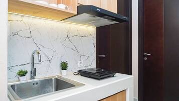 A modern kitchen with a marble backsplash, stainless steel sink, and a black range hood.