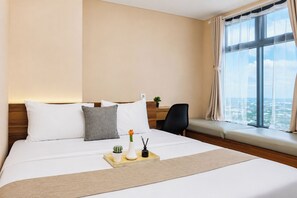 A hotel room with a large bed, a desk, a chair, a window with a view, and a tray with a plant and a vase. - Modern Look 2Br Apartment Pollux Chadstone (Cikarang)