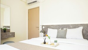Quarto de hotel com cama, mesa de cabeceira e espelho.