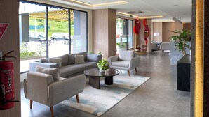 Um saguão de hotel moderno com um sofá, cadeiras, uma mesa de centro e um balcão de recepção.