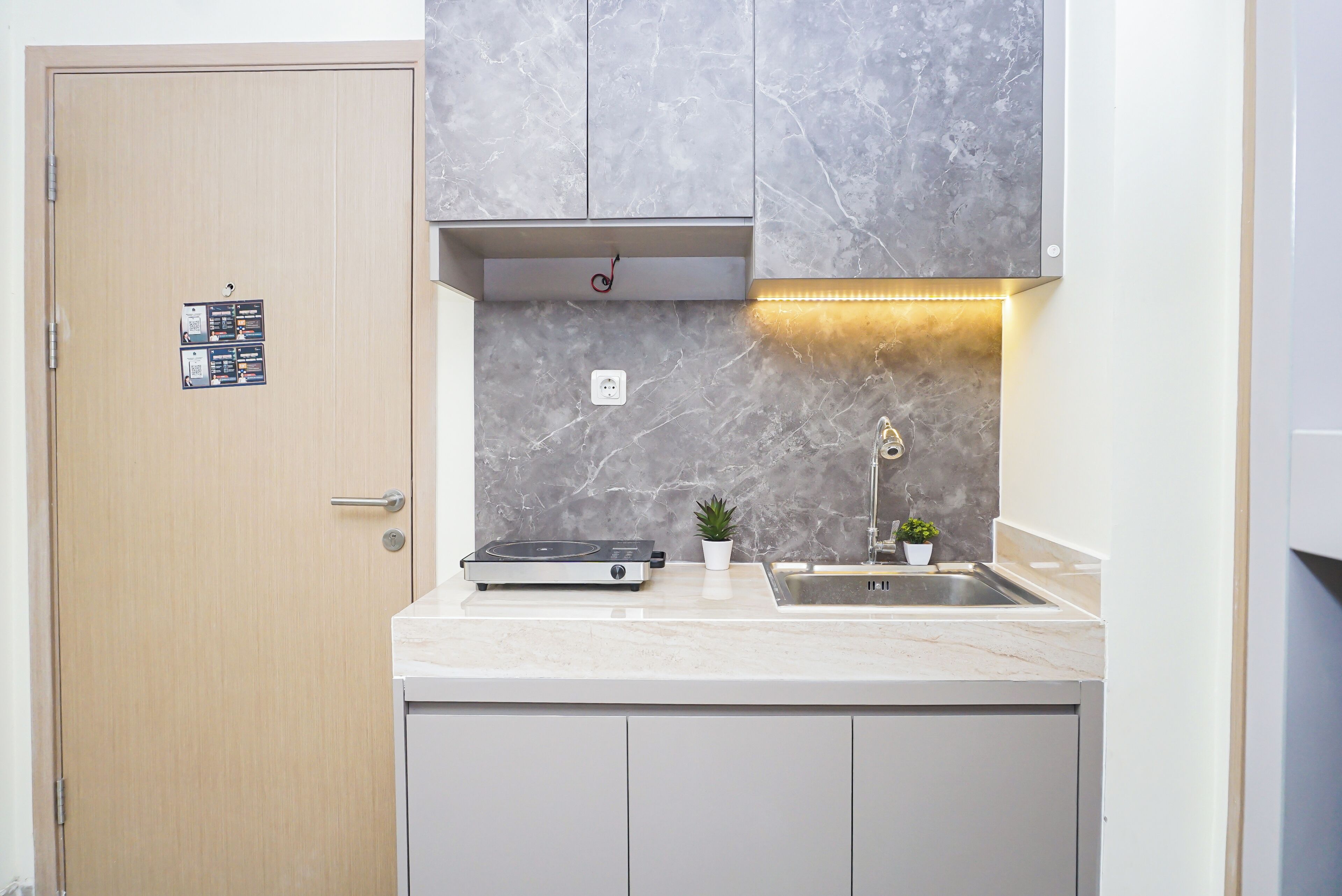 A compact kitchen with a built-in stove, a sink, and a small potted plant.