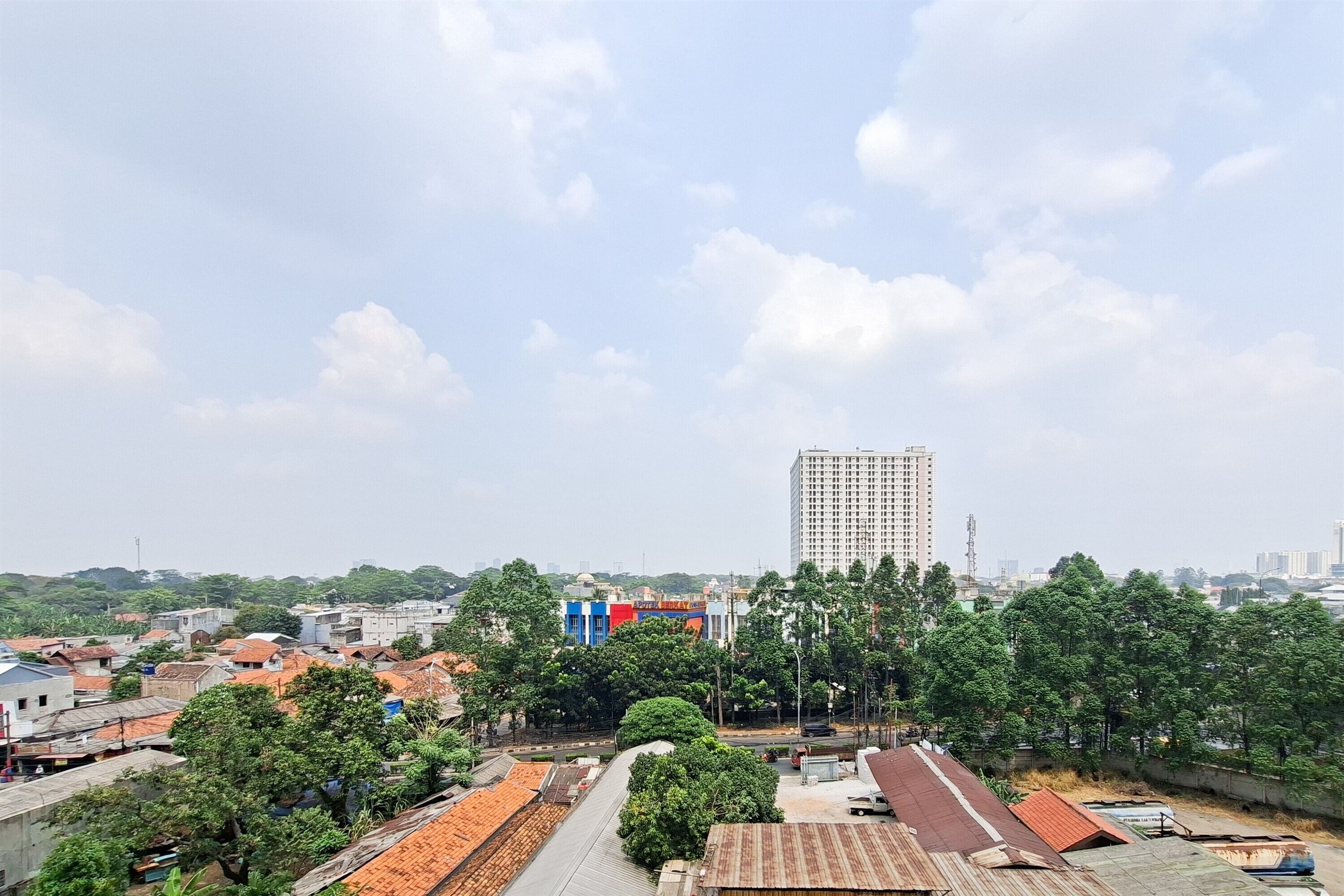 A cityscape with a prominent high-rise building, a mix of residential and commercial buildings, and a clear sky.