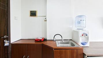 A small kitchenette with a sink, a water dispenser, and a red electric stove.