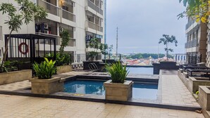 A rooftop pool area with a view of the cityscape, surrounded by potted plants and a lifebuoy. - Comfort Studio At Apartment Annora Living (Tangerang)
