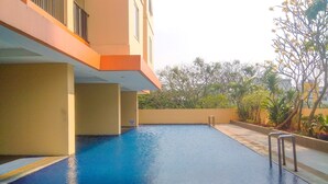 A swimming pool with a metal ladder, surrounded by a low wall and plants. - Elegant & Cozy Living 2Br Boutique Kemayoran Apartment Next To Citra Xperience Mall (Jakarta)