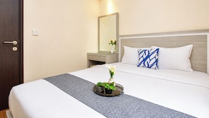 A hotel room with a bed, a bedside table, a mirror, and a vase with flowers. - Elegant & Cozy Living 2Br Boutique Kemayoran Apartment Next To Citra Xperience Mall (Jakarta)