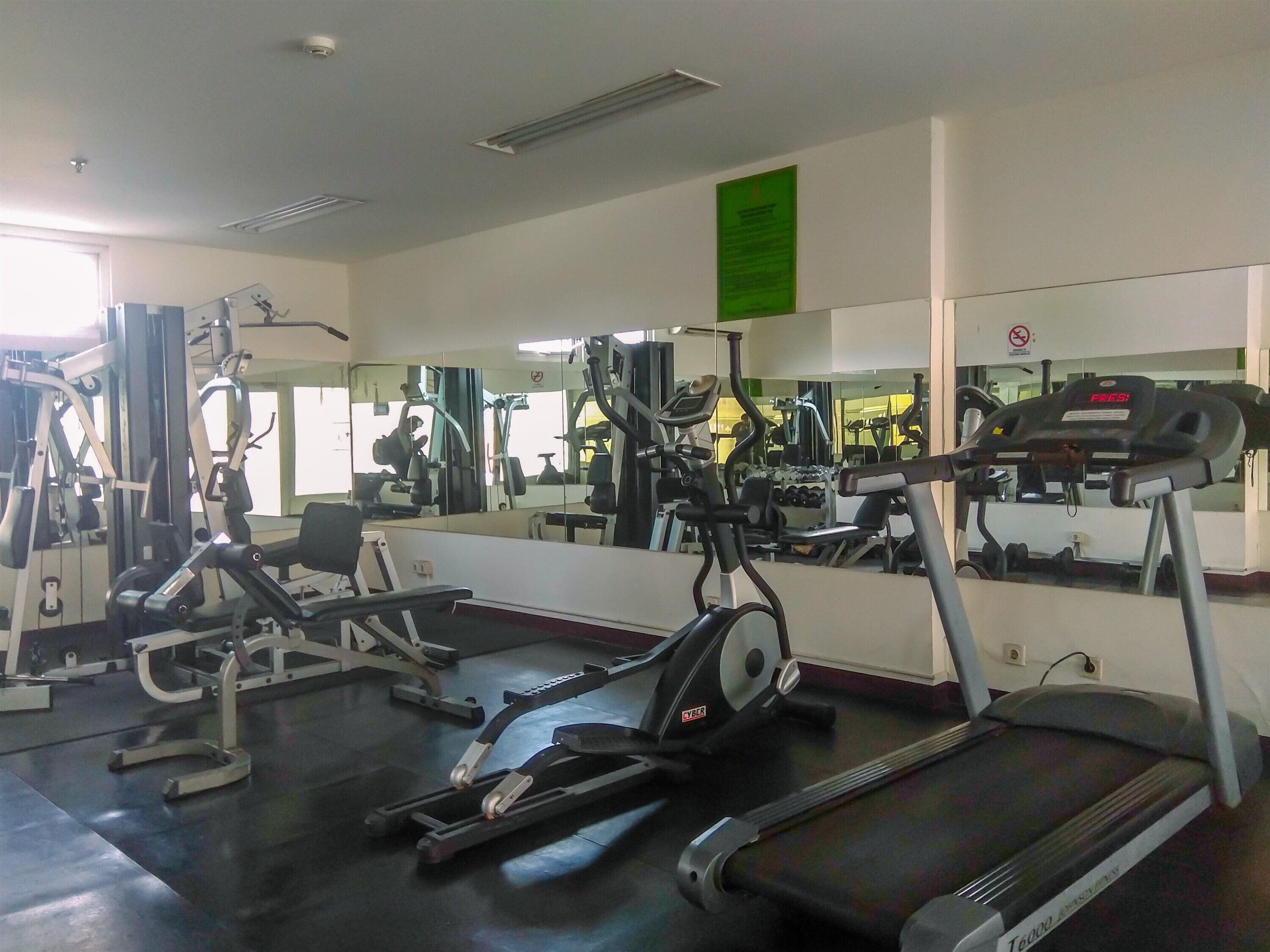 Ett gym med olika typer av träningsutrustning, inklusive löpband, crosstrainers och styrketräningsmaskiner.