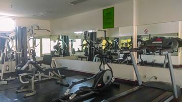 Ett gym med olika typer av träningsutrustning, inklusive löpband, crosstrainers och styrketräningsmaskiner.