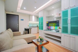 A modern living room with a sofa, a coffee table, and a TV on a stand. - Elegant & Cozy Living 2Br Boutique Kemayoran Apartment Next To Citra Xperience Mall (Jakarta)