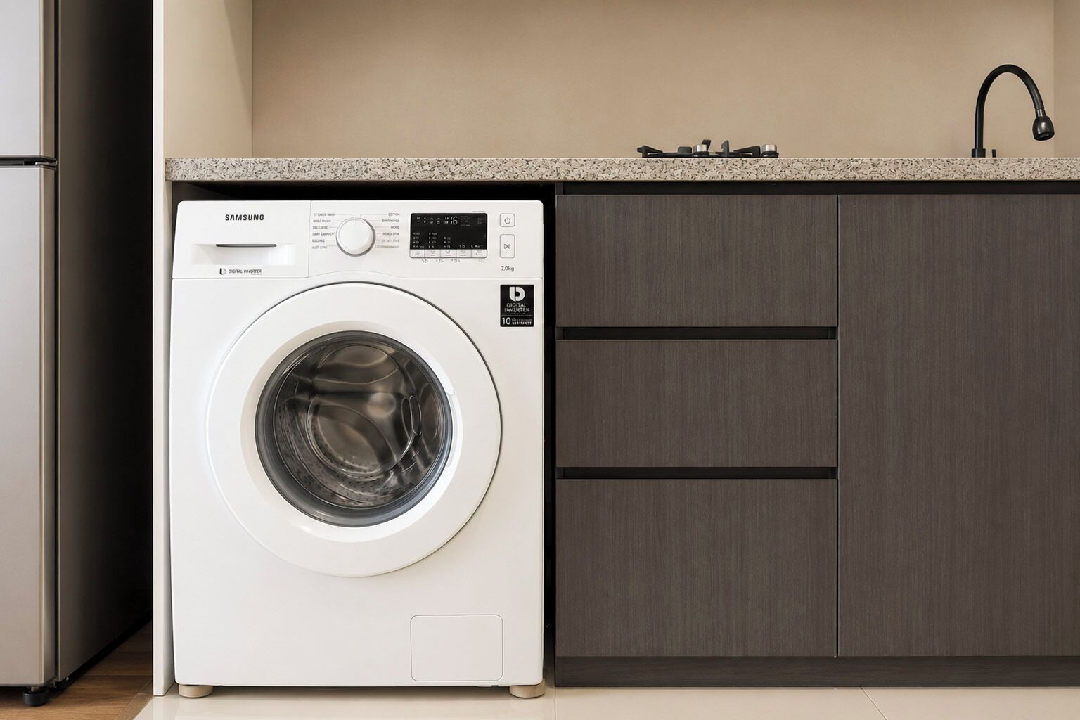 Lavadora Samsung de carga frontal en una cocina moderna con encimera de granito y armarios de madera oscura.