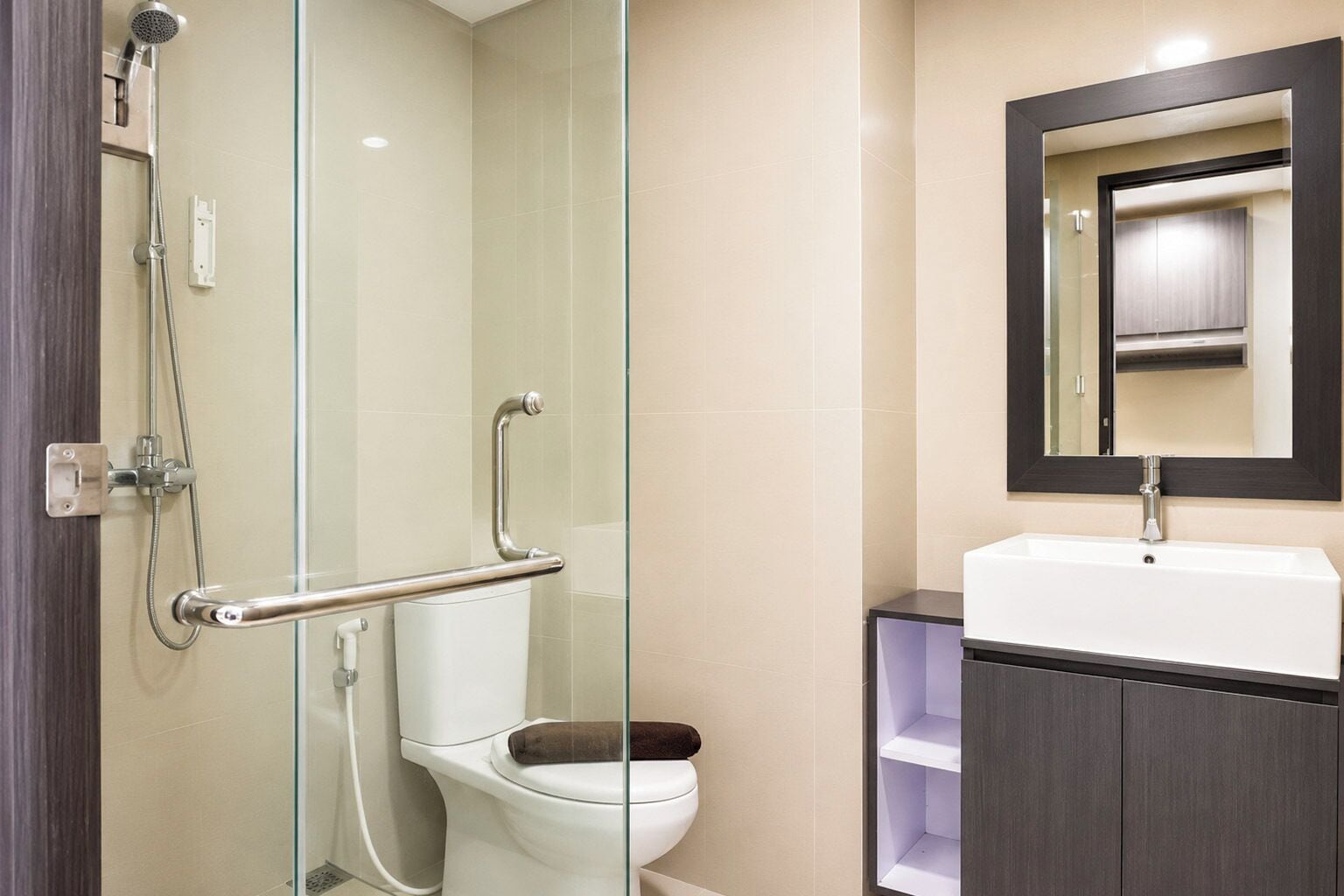 Un baño moderno con cabina de ducha de vidrio, inodoro blanco y tocador con espejo.