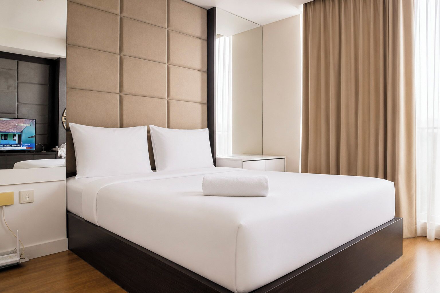 Une chambre d’hôtel moderne dotée d’un grand lit, d’un téléviseur à écran plat, d’une table de chevet et d’une fenêtre avec des rideaux.
